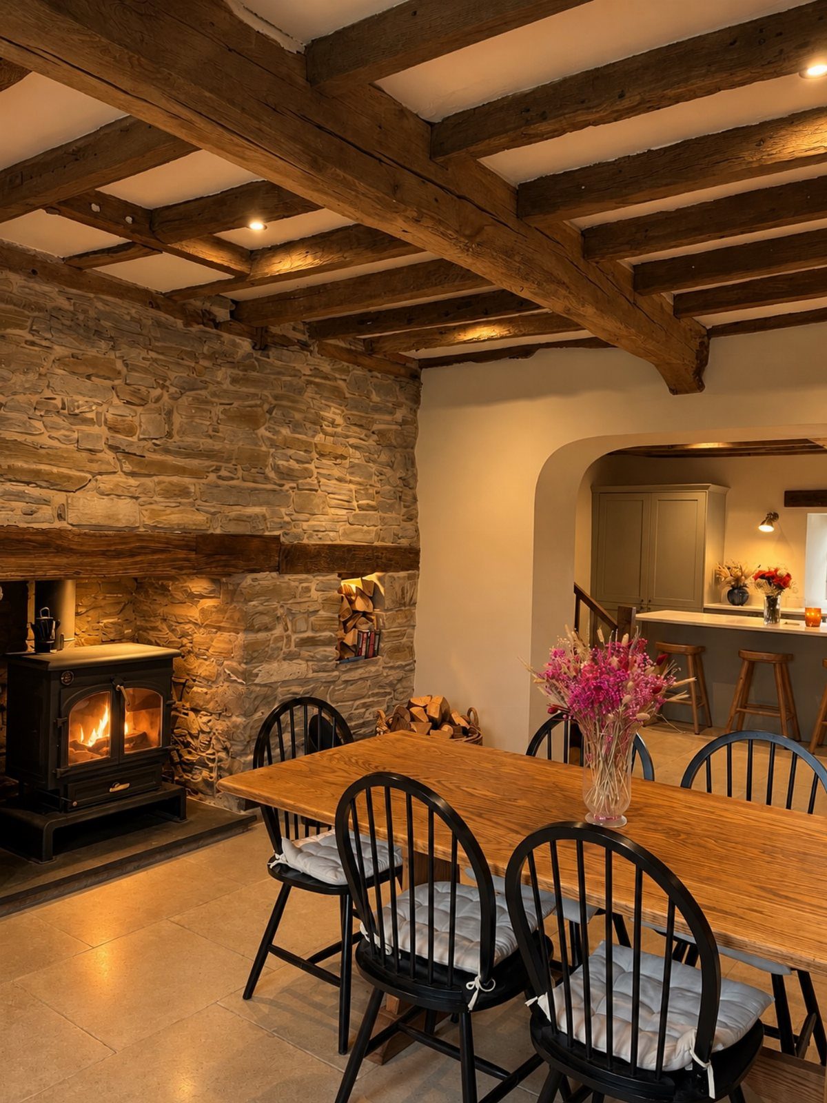 Dark wood ceiling beams above a rustic dining table and stone fireplace wall.
