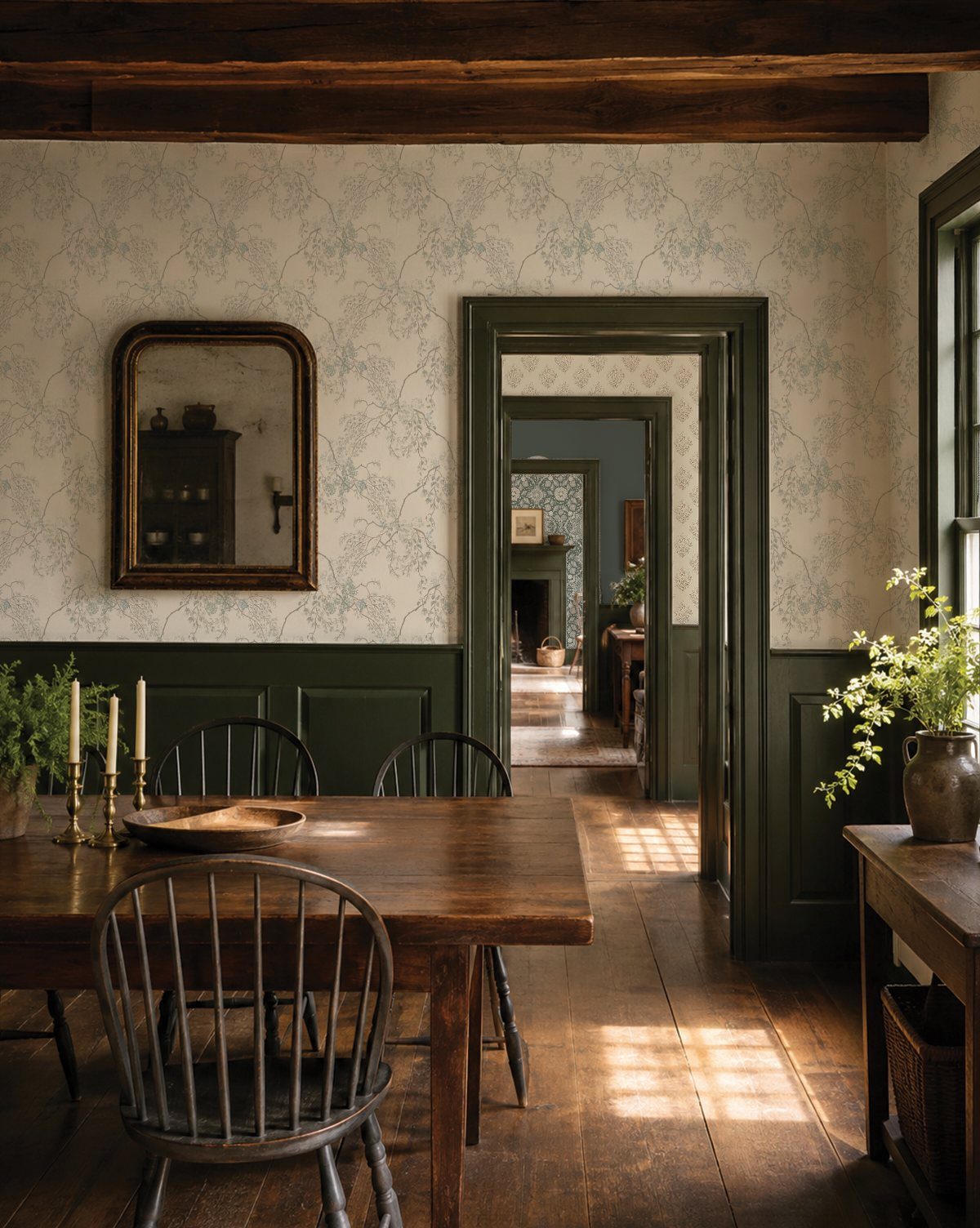 Dark wood dining table and chairs in a room with green wainscoting.