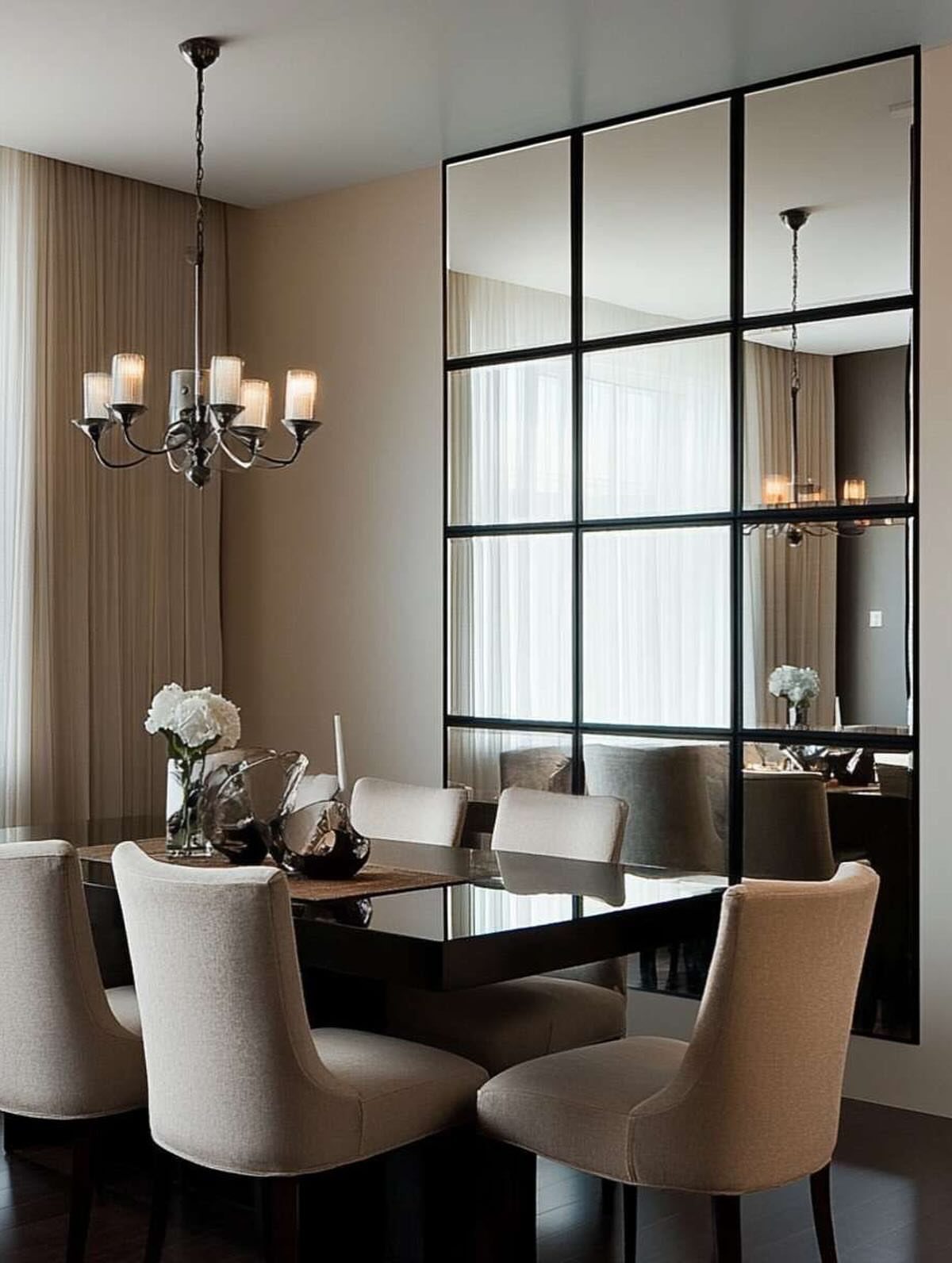 Dining room with beige chairs and a large black-framed grid wall mirror.