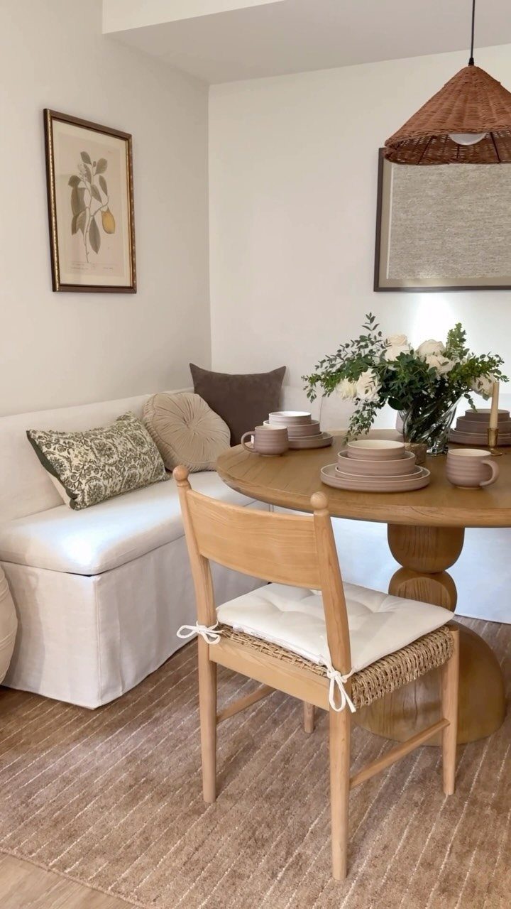 Corner banquette with white cushions and a round wooden table with a matching chair.