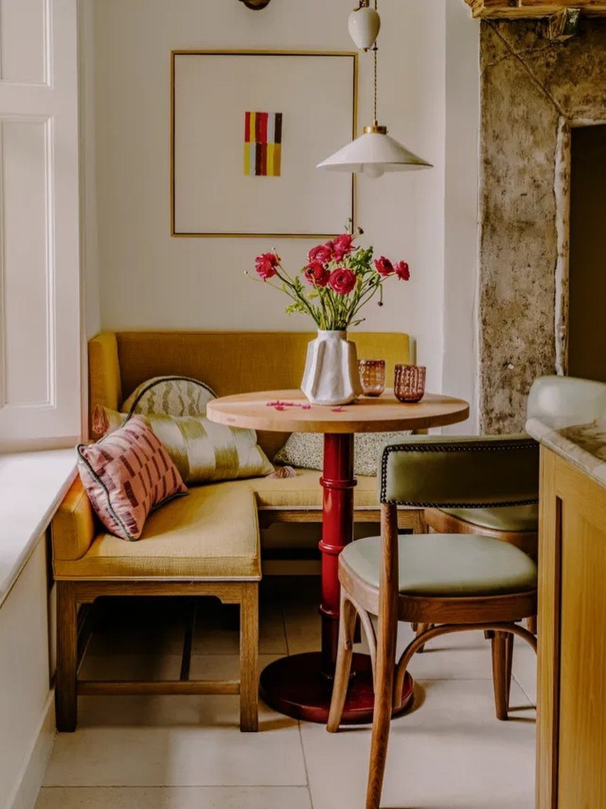 Yellow L-shaped corner banquette with a round wooden table and green chair.