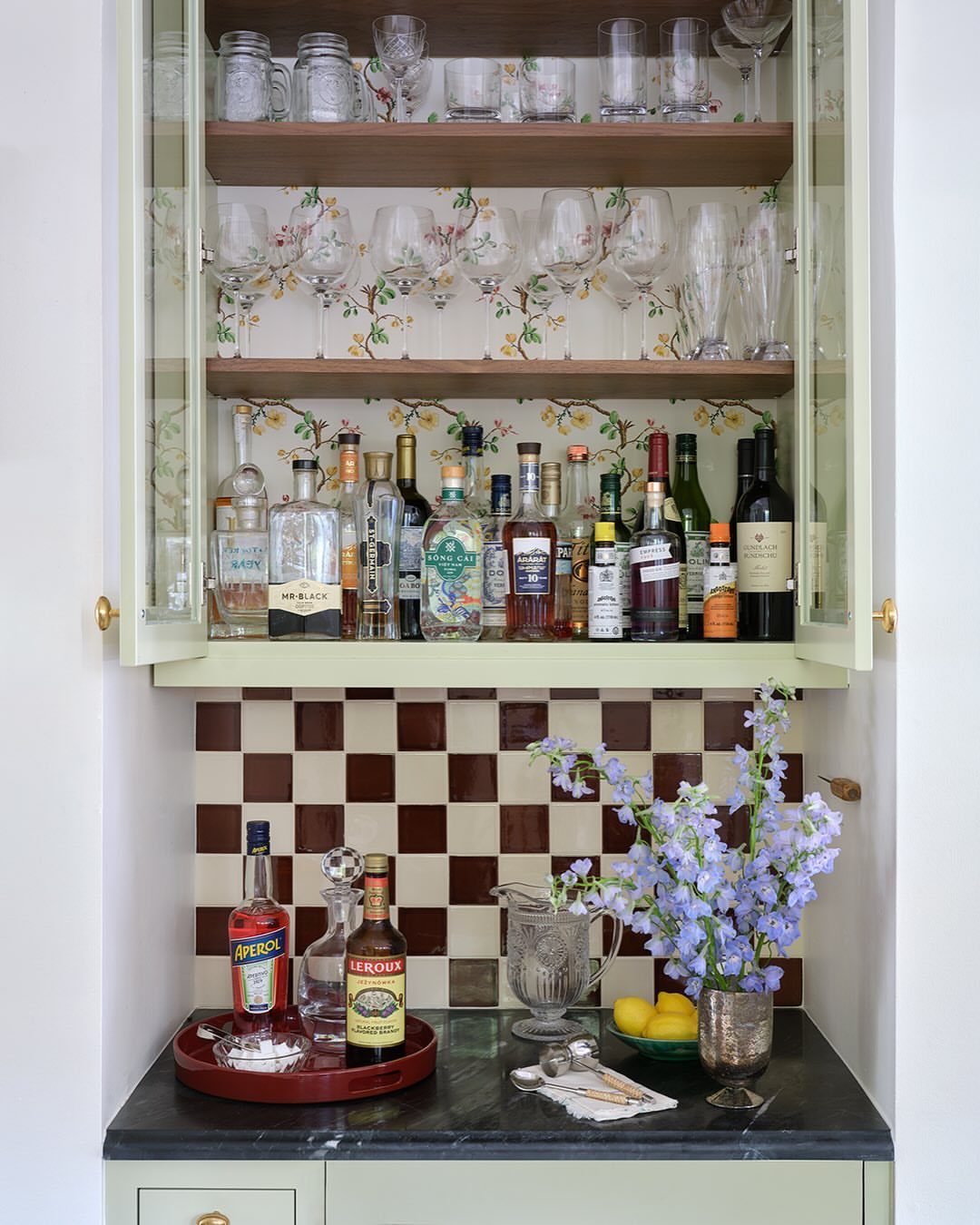 Dining Room Side Cabinet Designs with 18 Stylish Options 18 Built-in home bar cabinet with liquor bottles, glassware, and floral wallpaper interior.