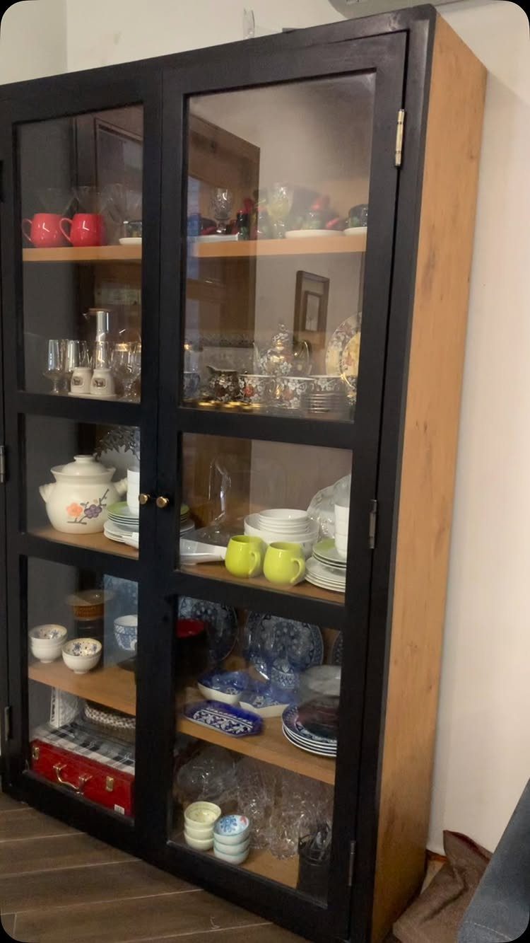 Dining Room Side Cabinet Designs with 18 Stylish Options 2 Tall black glass-door cabinet filled with colorful dishes and glassware on wooden shelves.