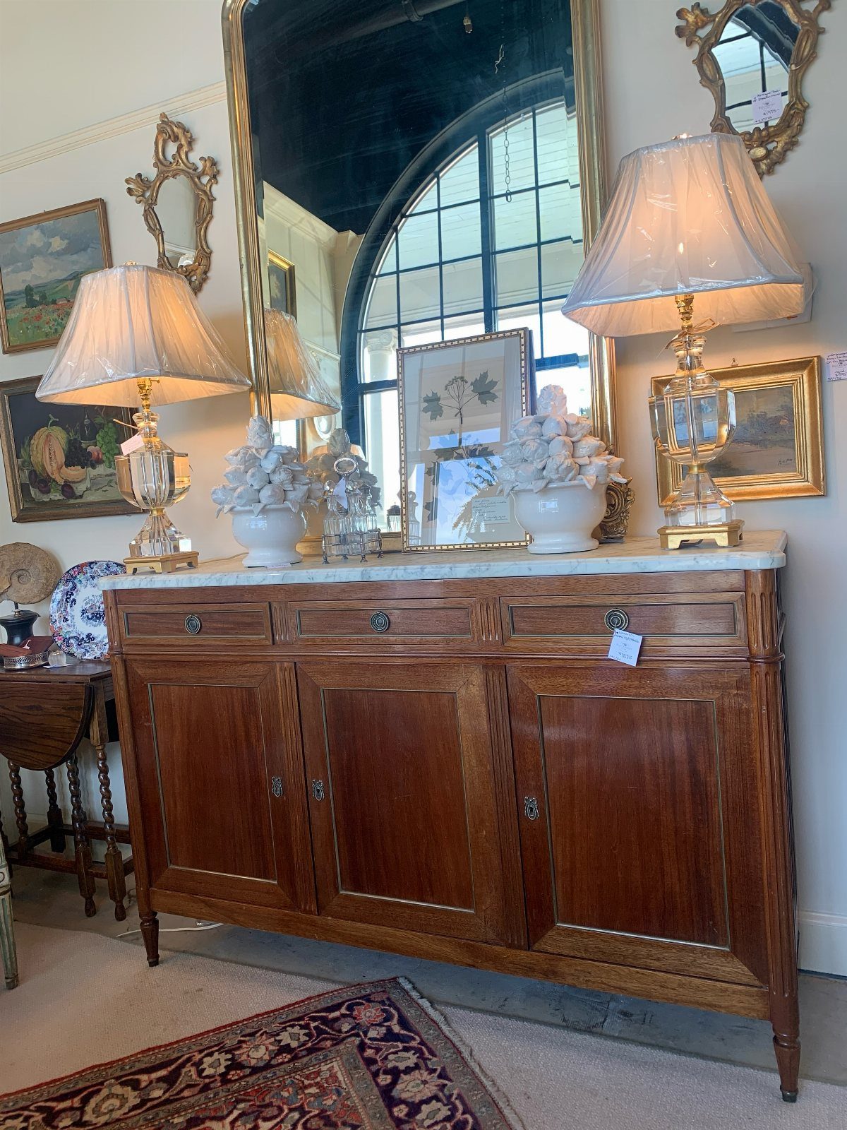 Dining Room Side Cabinet Designs with 18 Stylish Options 16 Wooden sideboard with white marble top, lamps, and a large gold mirror behind it.