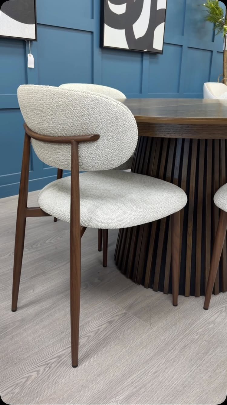 White upholstered dining chair with dark wood legs next to a fluted table.