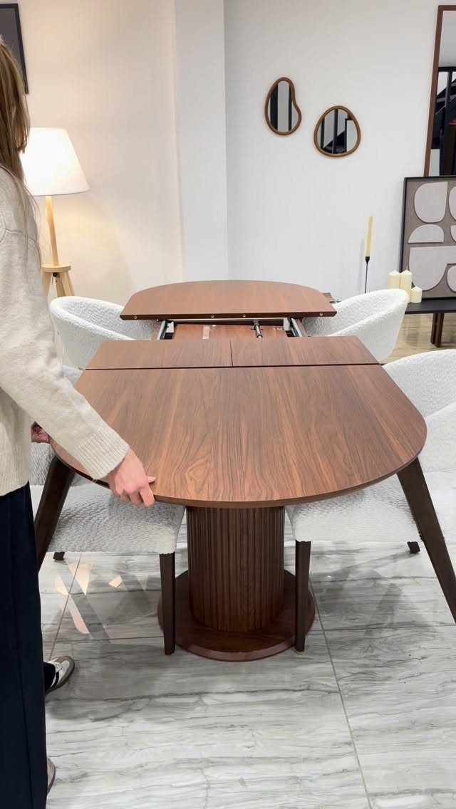 Dark wood extendable dining table with white upholstered chairs on marble floor