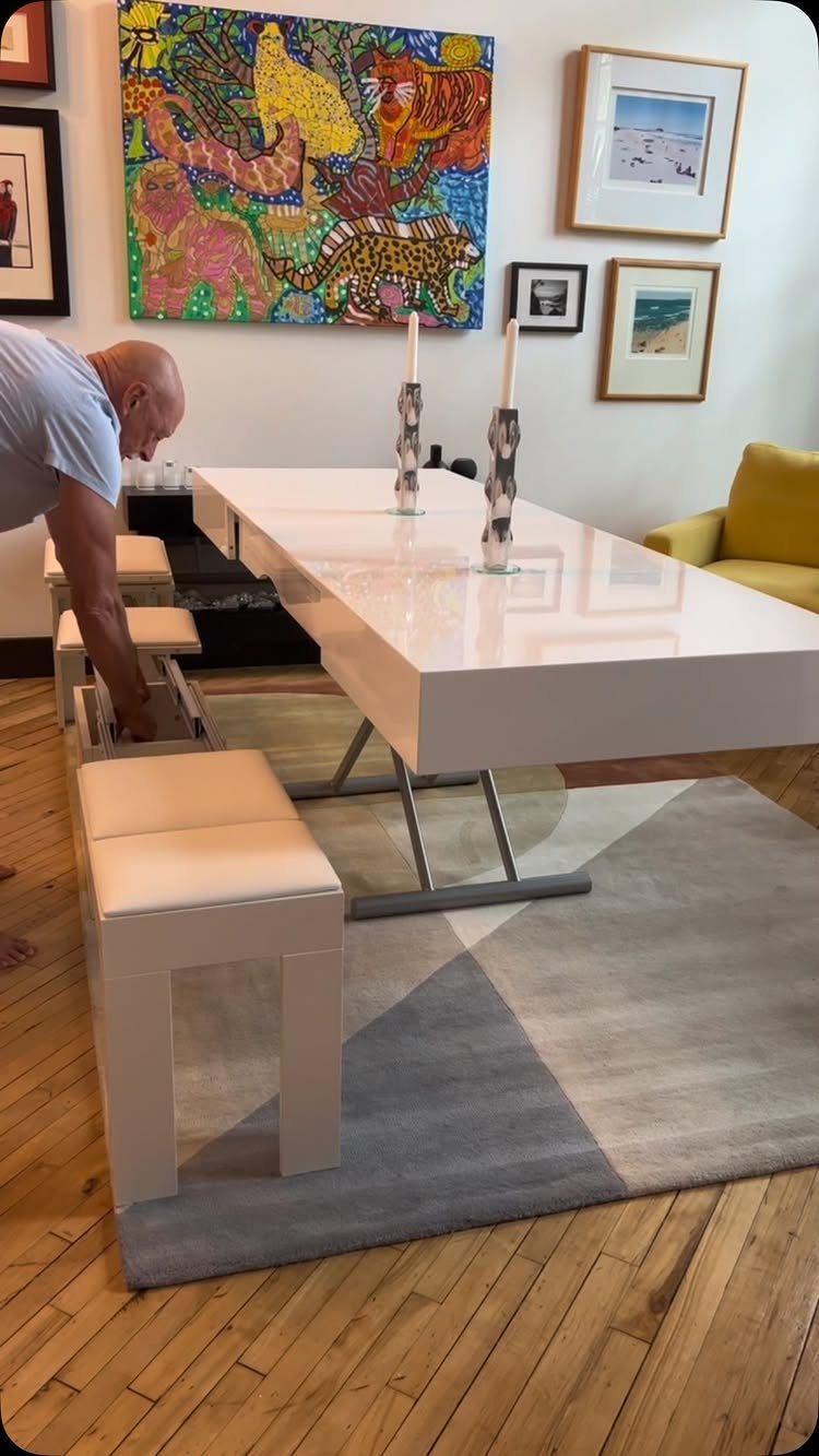 White rectangular high-gloss dining table with matching benches on a geometric rug.