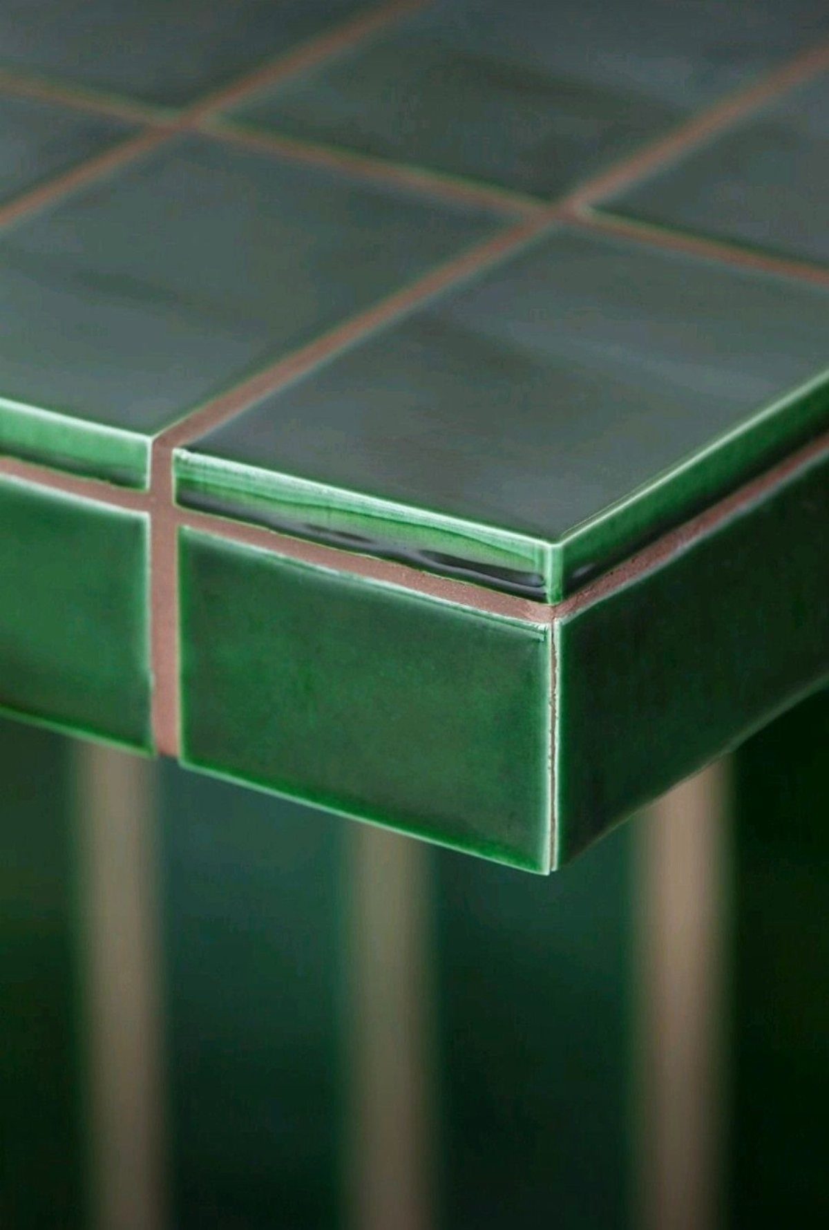 Glossy green ceramic tile countertop with light grout lines in a close-up view.