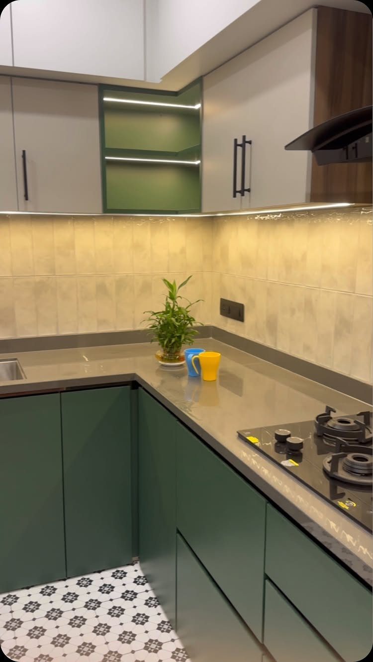 Grey kitchen countertops with dark green cabinets and a small potted plant.