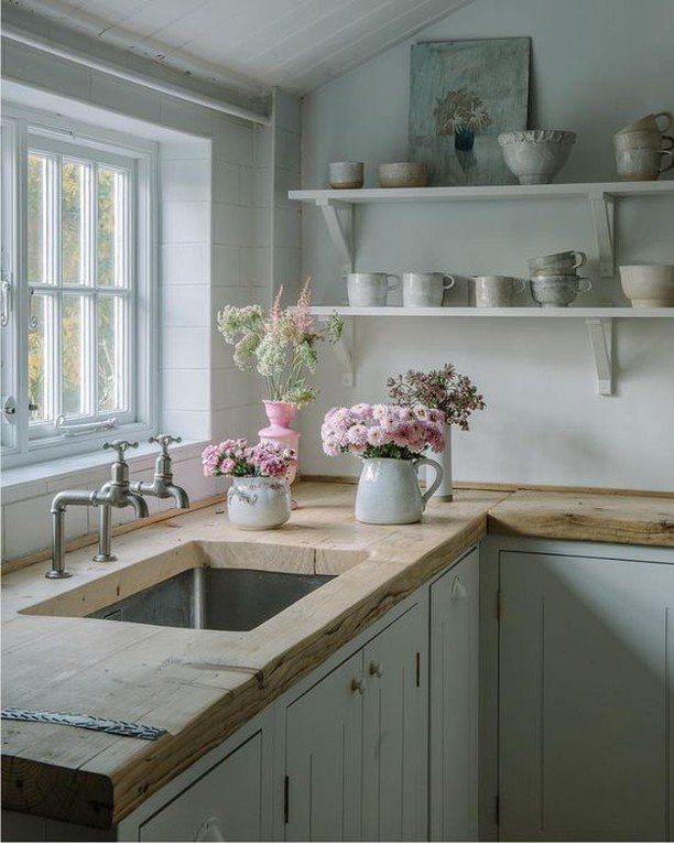 Wooden kitchen countertops with a built-in sink and pink flowers in a rustic kitchen
