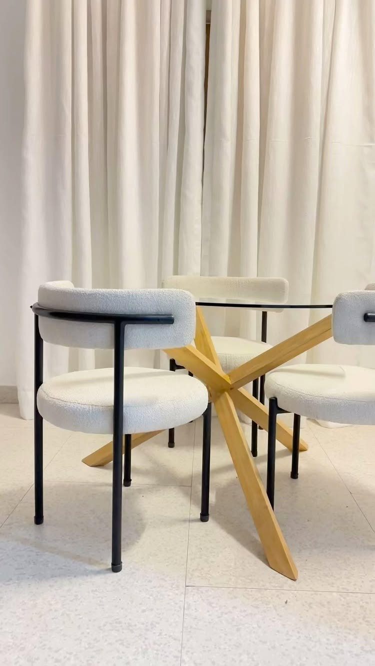 Fabric Chairs Dining Ideas: 32 Styles, Colors, and Frames 9 White fabric dining chairs with black frames around a glass table with wooden legs.