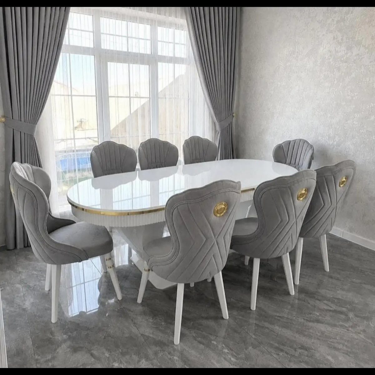 Fabric Chairs Dining Ideas: 32 Styles, Colors, and Frames 21 Gray upholstered dining chairs with gold accents around a white oval dining table.