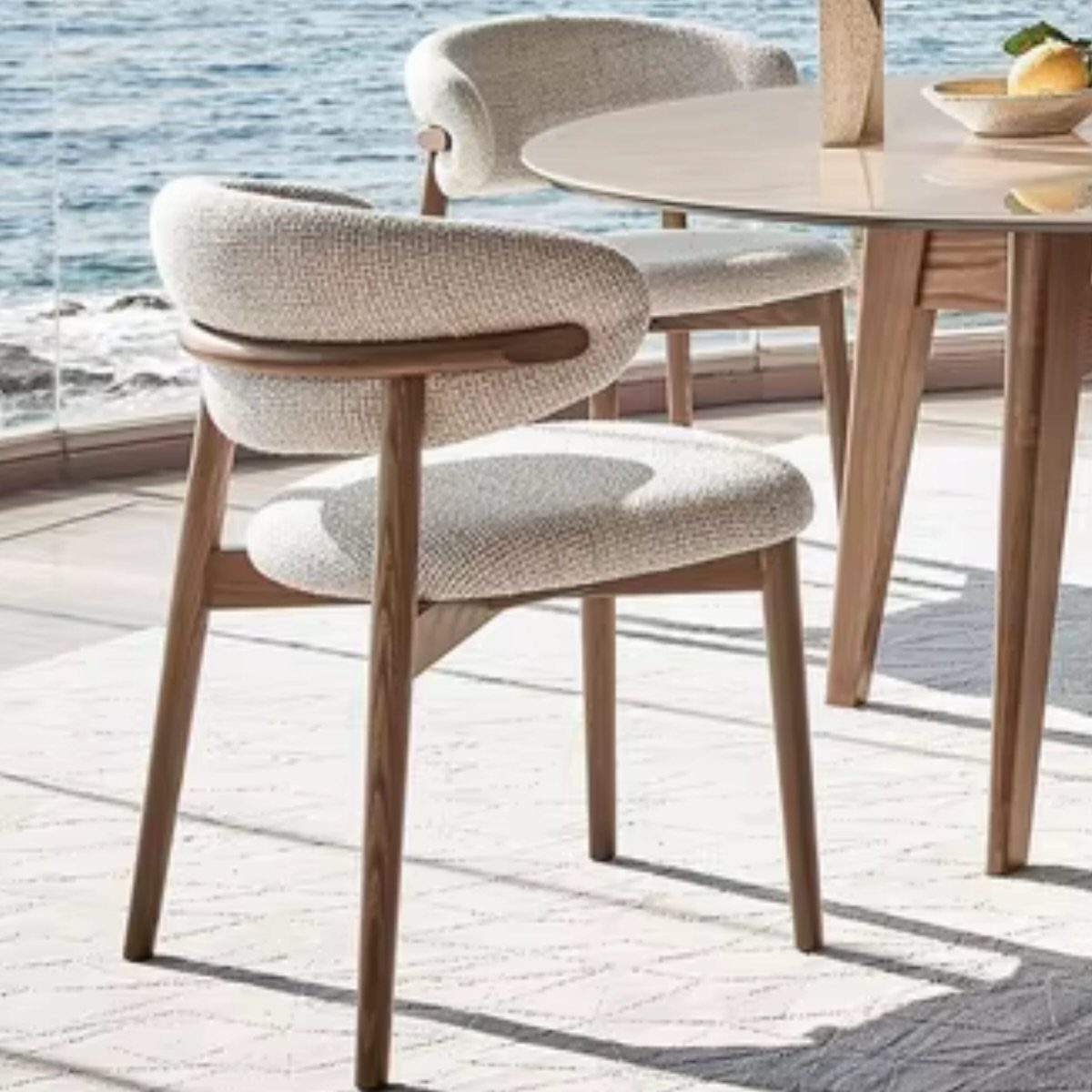 Fabric Chairs Dining Ideas: 32 Styles, Colors, and Frames 31 Light fabric dining chairs with wooden legs and a round white table outdoors.