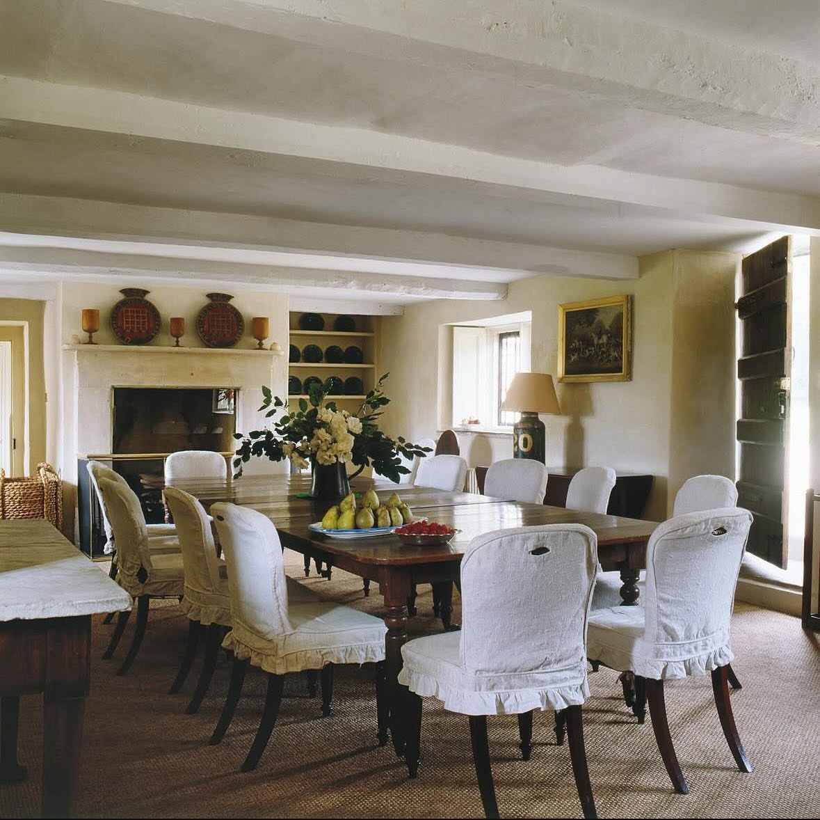 Fabric Chairs Dining Ideas: 32 Styles, Colors, and Frames 11 White slipcovered fabric dining chairs around a long rustic wooden dining table.