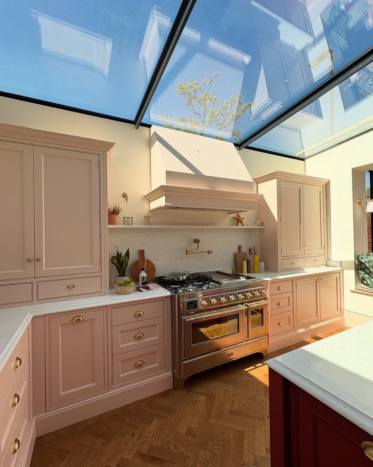 35 Farmhouse Kitchen Remodel Ideas Worth Stealing 27 Pale pink kitchen with gold hardware, copper stove, and a glass ceiling.