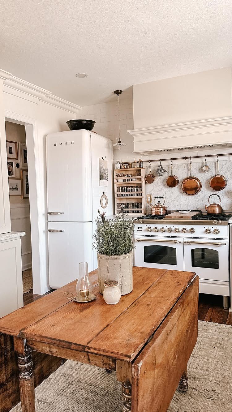35 Farmhouse Kitchen Remodel Ideas Worth Stealing 6 Rustic wooden farmhouse table in a bright kitchen with vintage white appliances.