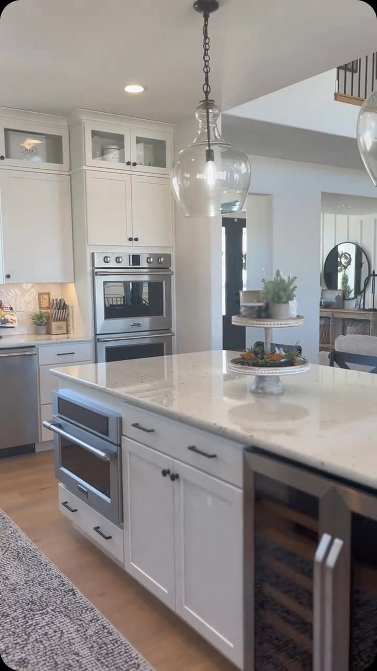 35 Farmhouse Kitchen Remodel Ideas Worth Stealing 33 White farmhouse kitchen with marble island and glass-front upper cabinets.