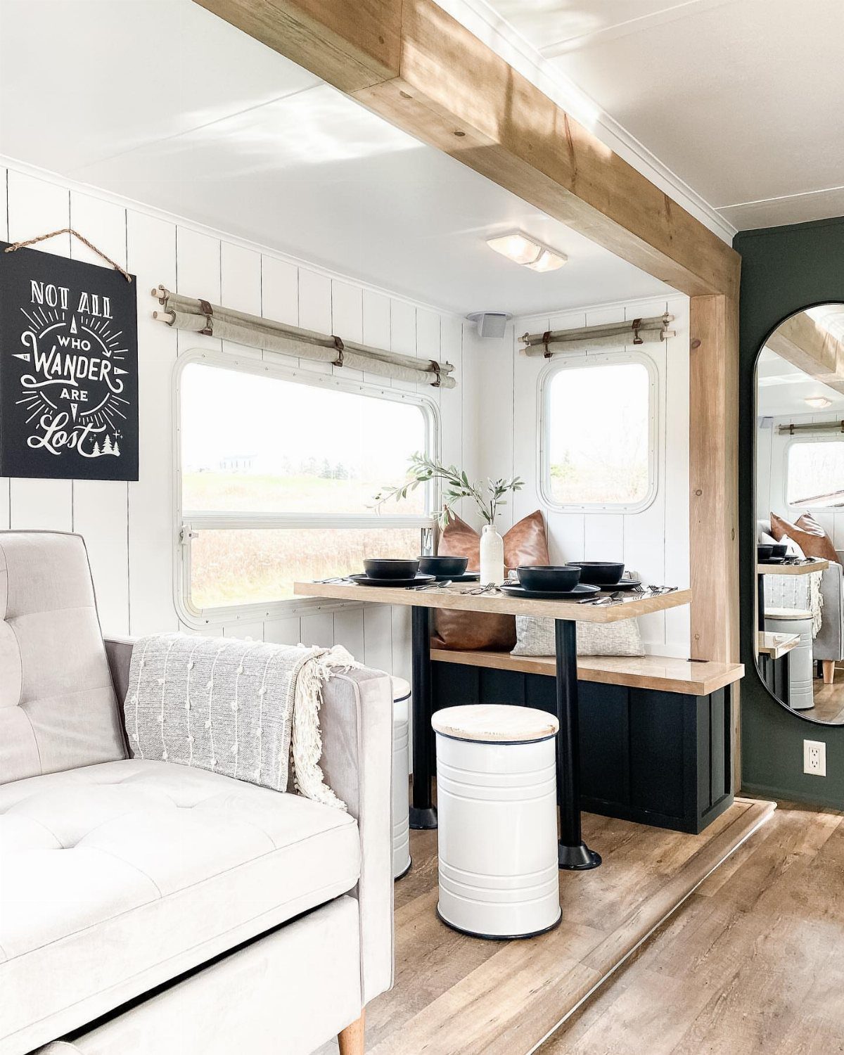 23 Fifth Wheel Remodel Ideas for Storage, Color, and Comfort 6 Remodeled RV interior with white paneled walls, wooden ceiling beam, and dining nook.