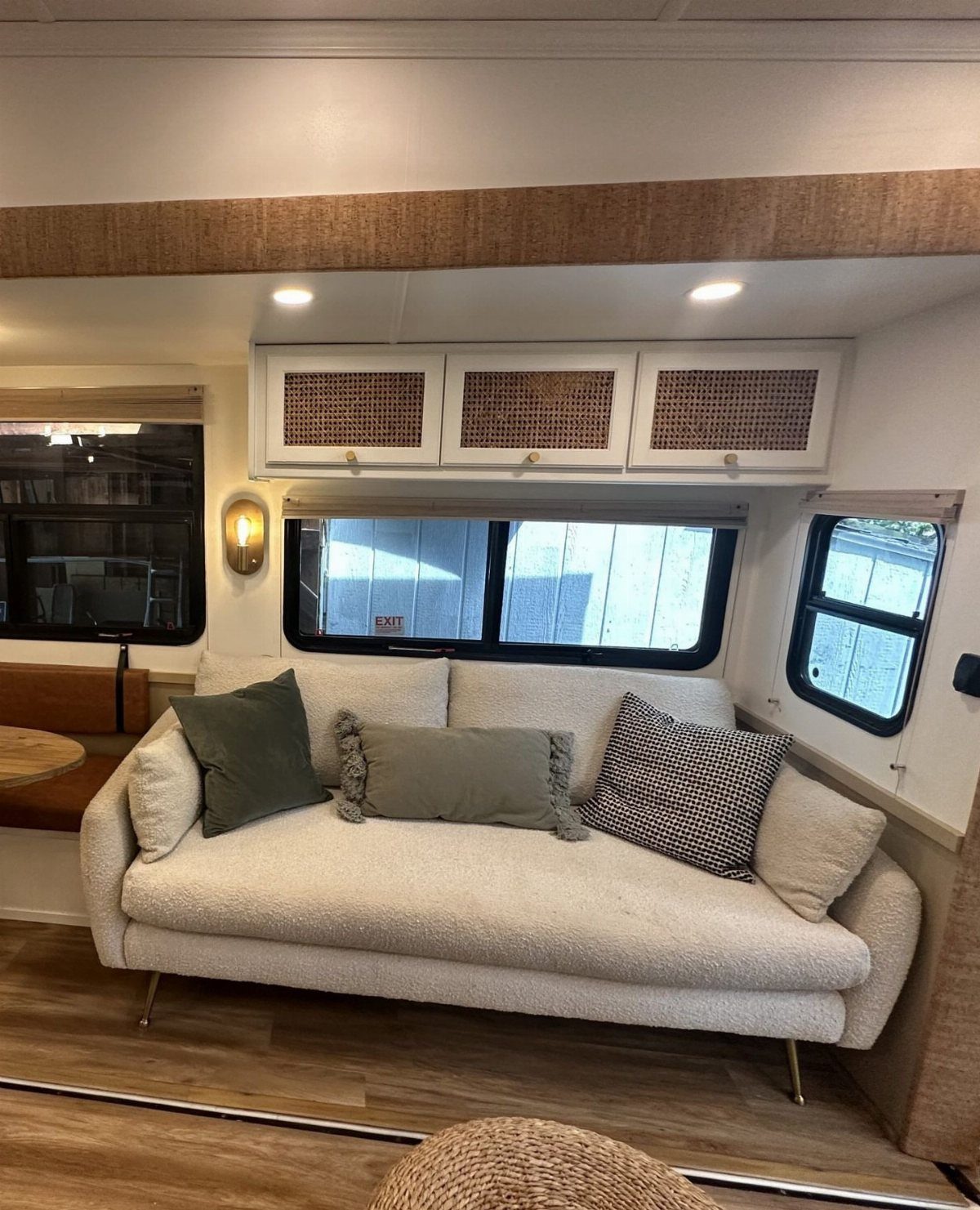 23 Fifth Wheel Remodel Ideas for Storage, Color, and Comfort 19 Remodeled fifth wheel interior with a white bouclé sofa and cane-front overhead cabinets.