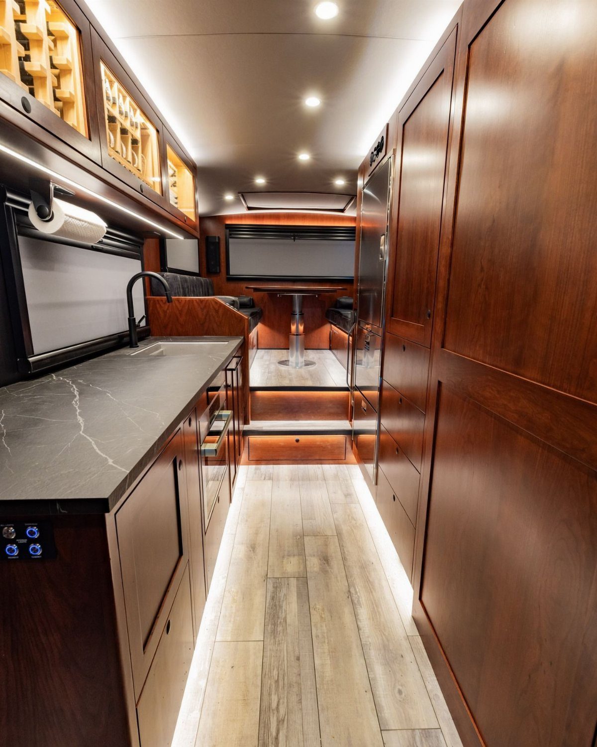 23 Fifth Wheel Remodel Ideas for Storage, Color, and Comfort 8 Luxury RV interior with dark wood cabinets and built-in illuminated wine racks.