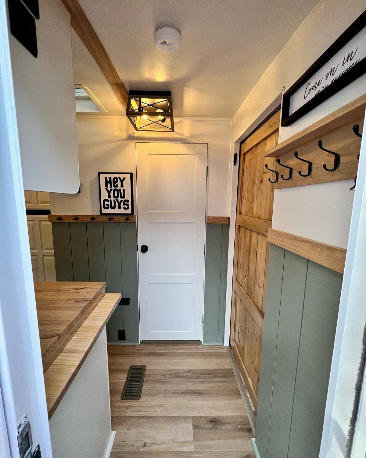 23 Fifth Wheel Remodel Ideas for Storage, Color, and Comfort 13 White paneled RV entry door with sage green wainscoting and wooden accents.