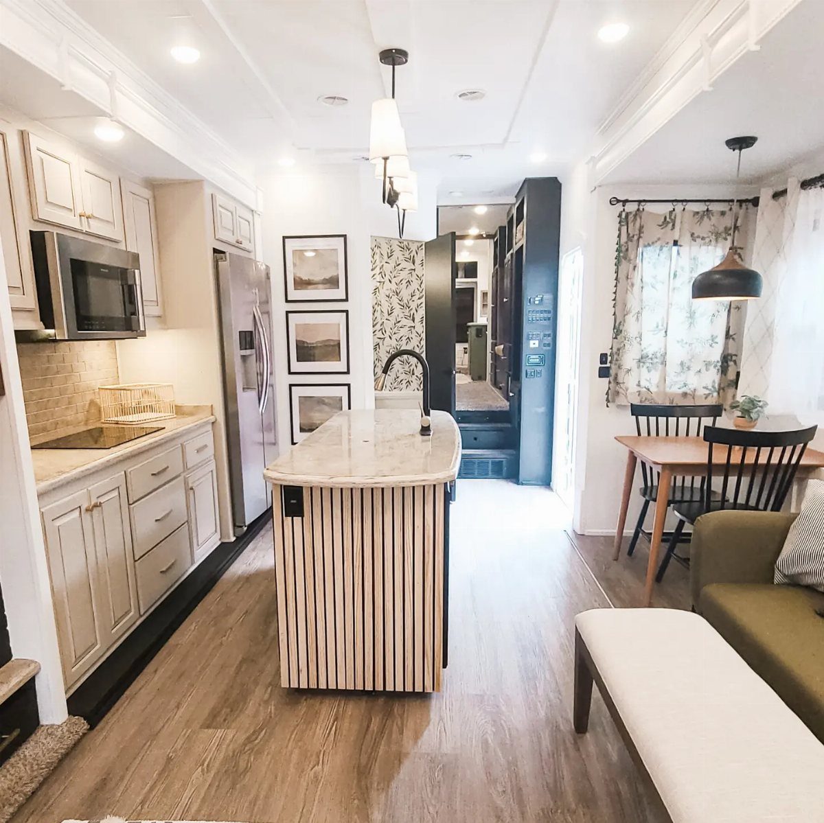 23 Fifth Wheel Remodel Ideas for Storage, Color, and Comfort 20 Modern fifth wheel interior with white cabinets, wood island, and dining area.