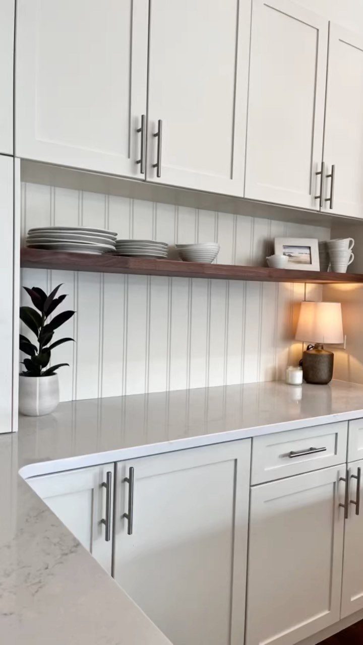 23 Fifth Wheel Remodel Ideas for Storage, Color, and Comfort 18 White kitchen cabinets and quartz countertops with a wooden floating shelf and beadboard backsplash.