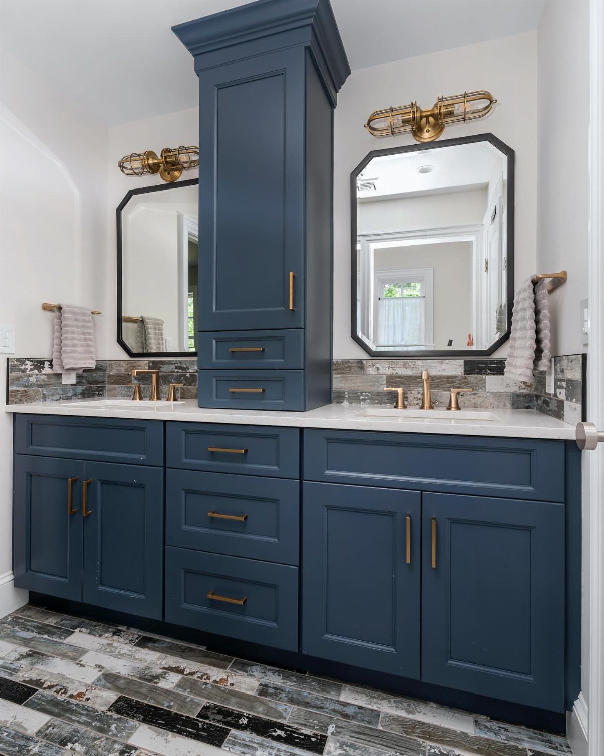 17 Jack and Jill Bathroom Remodel Ideas for Shared Spaces 10 Dark blue bathroom vanity with white countertops and gold hardware against light walls.