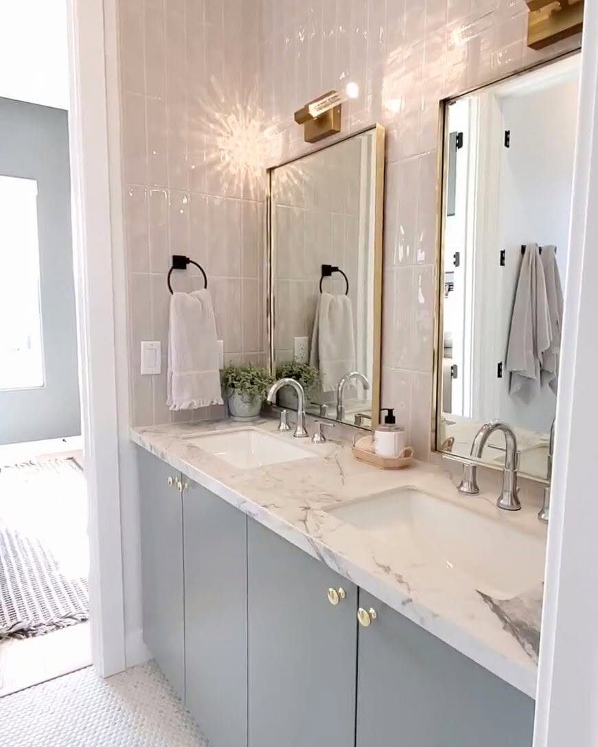 17 Jack and Jill Bathroom Remodel Ideas for Shared Spaces 7 Double vanity with light gray cabinets and marble countertops in a bright bathroom.