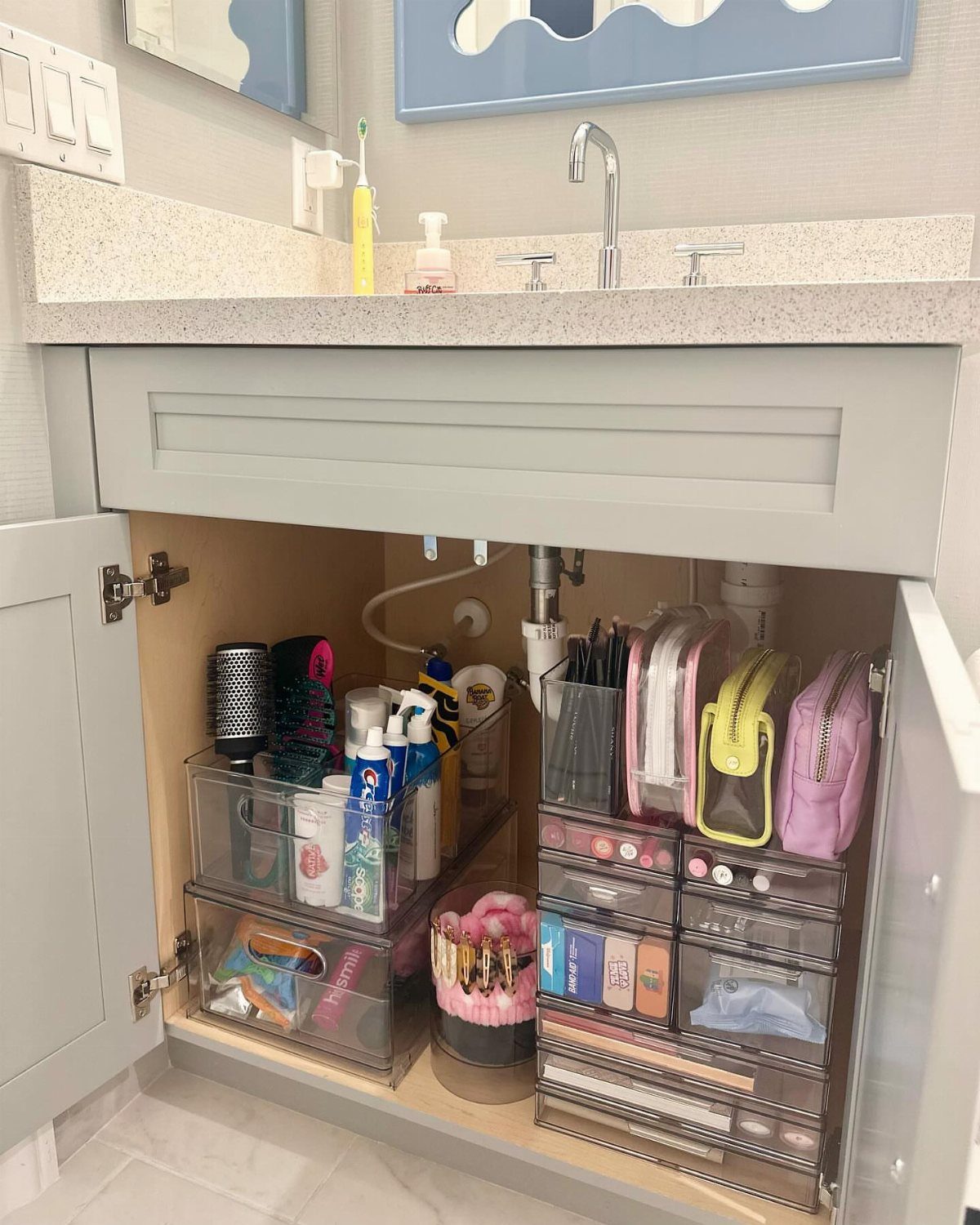 17 Jack and Jill Bathroom Remodel Ideas for Shared Spaces 5 Open grey bathroom vanity cabinet organized with clear plastic storage bins and drawers.