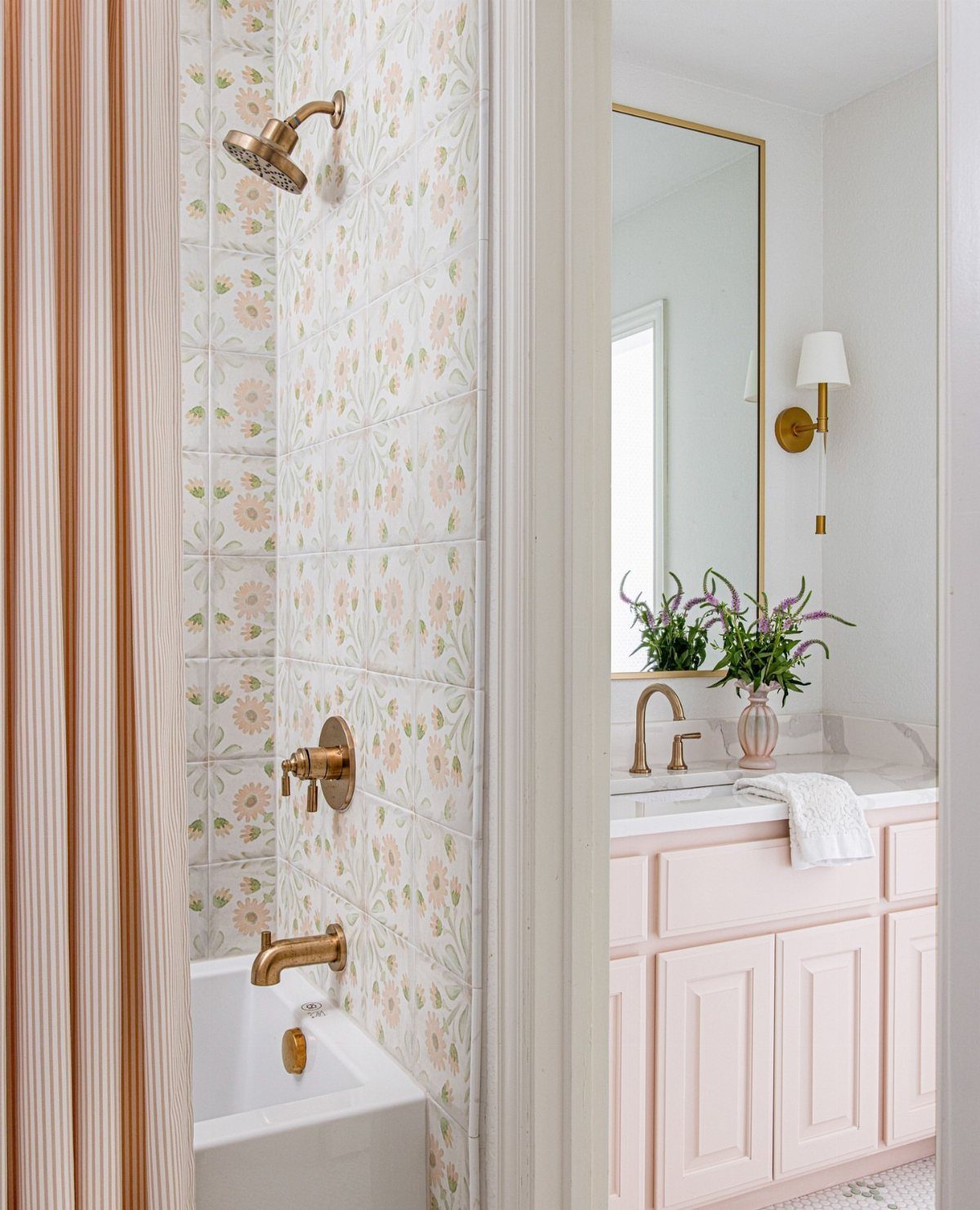 17 Jack and Jill Bathroom Remodel Ideas for Shared Spaces 14 White bathtub with gold fixtures and a pink vanity in a bright bathroom.