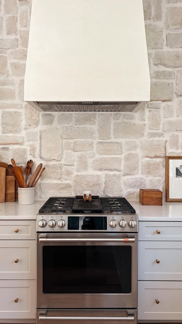 28 Kitchen Cabinets Remodel Ideas and Photos to Try in 2026 17 Light stone tile backsplash behind a stainless steel stove and white range hood.