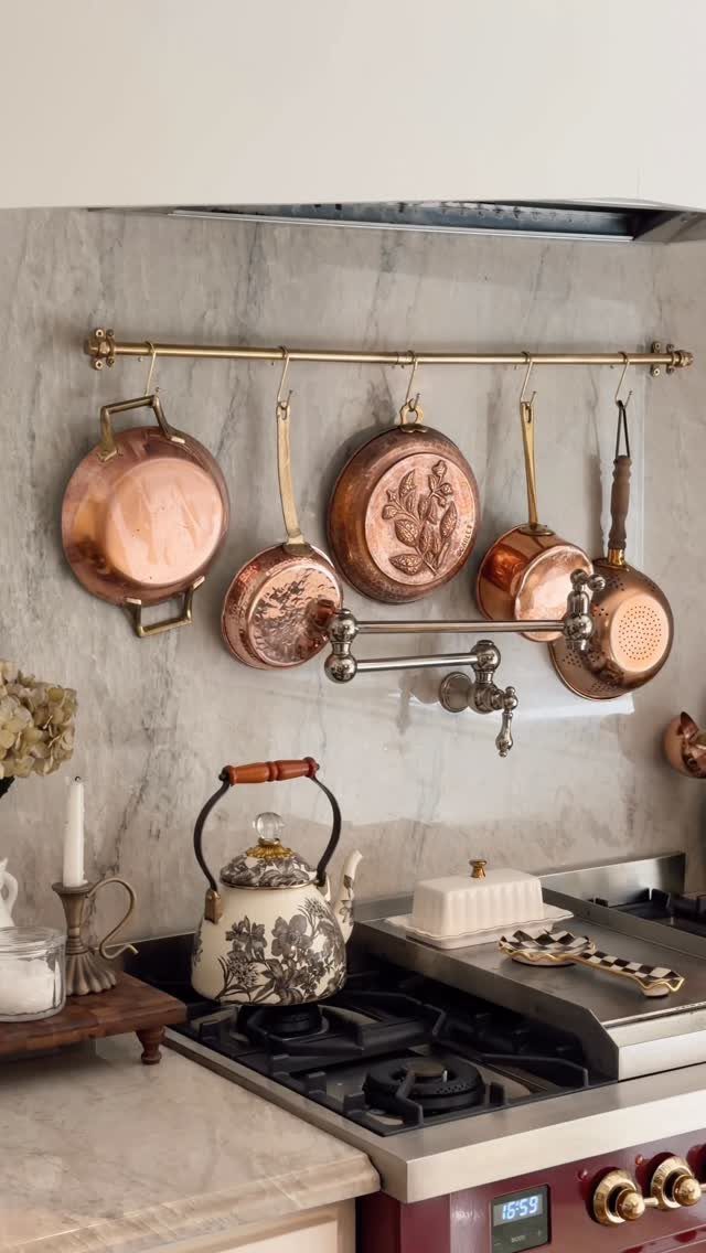 28 Kitchen Cabinets Remodel Ideas and Photos to Try in 2026 24 Copper pots and pans hanging from a brass rail over a gas stove.
