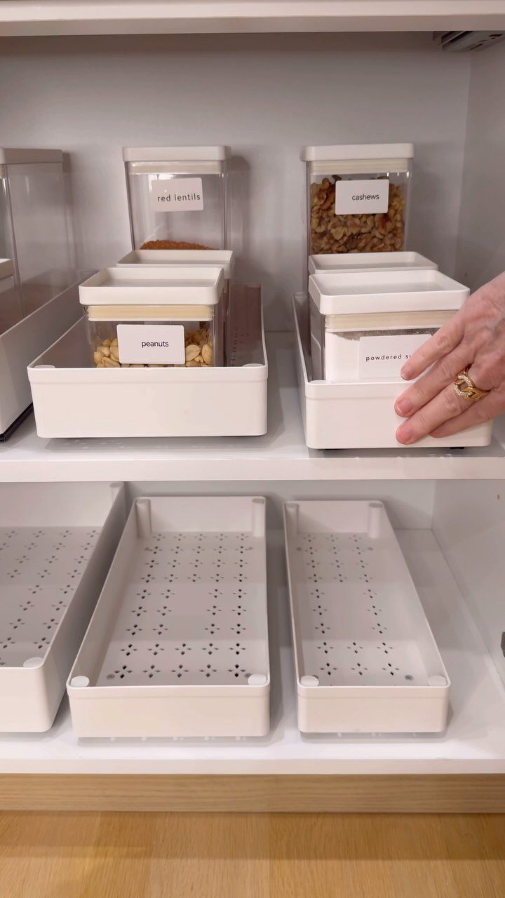 28 Kitchen Cabinets Remodel Ideas and Photos to Try in 2026 5 White plastic bins and clear labeled containers organized inside a white kitchen cabinet.