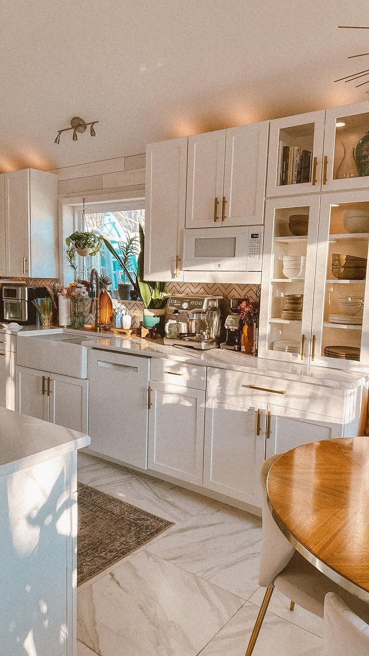 28 Kitchen Cabinets Remodel Ideas and Photos to Try in 2026 22 White kitchen with gold hardware and small green plants on the countertop.
