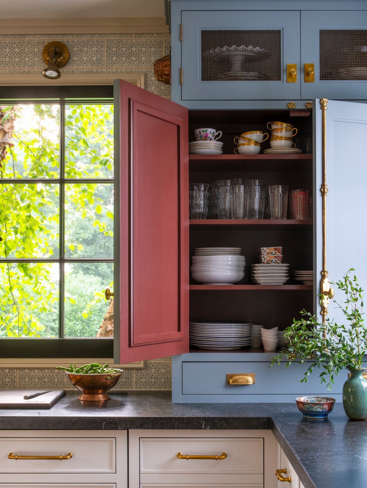 28 Kitchen Cabinets Remodel Ideas and Photos to Try in 2026 14 Blue kitchen cabinet with a contrasting red painted interior holding white dishes.