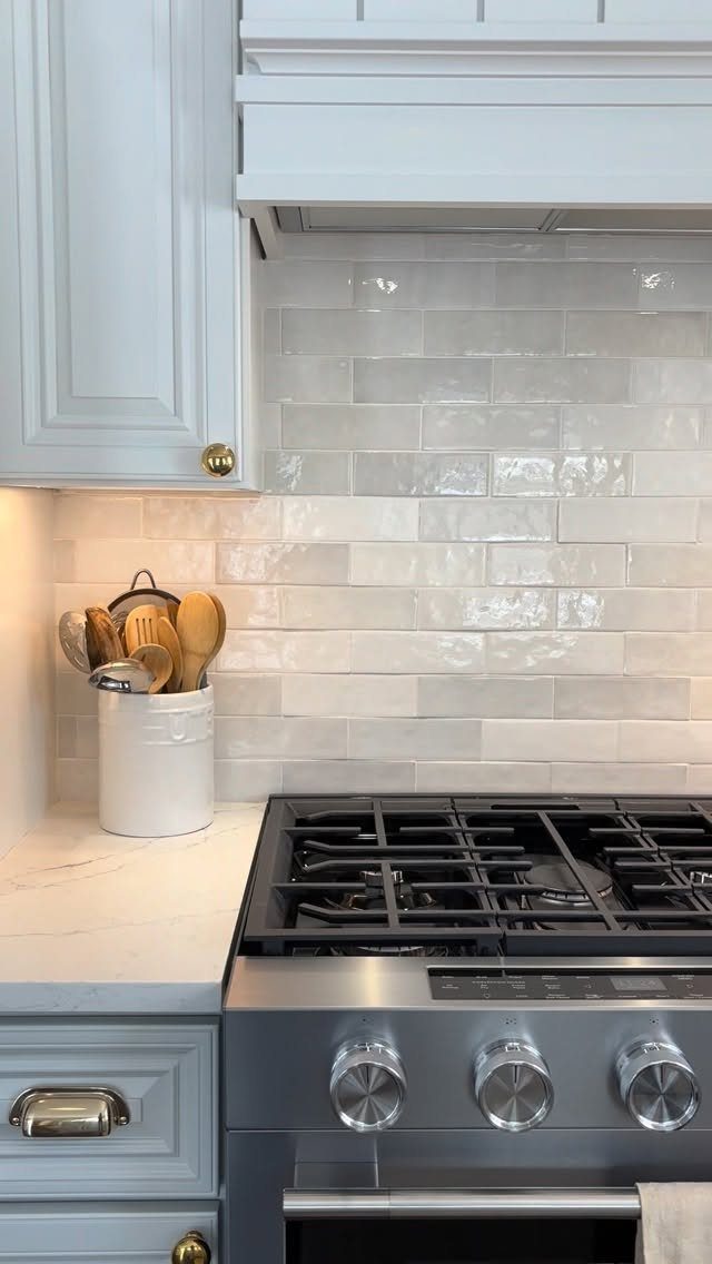 28 Kitchen Cabinets Remodel Ideas and Photos to Try in 2026 3 Light grey kitchen cabinets with gold hardware next to a stainless steel stove.