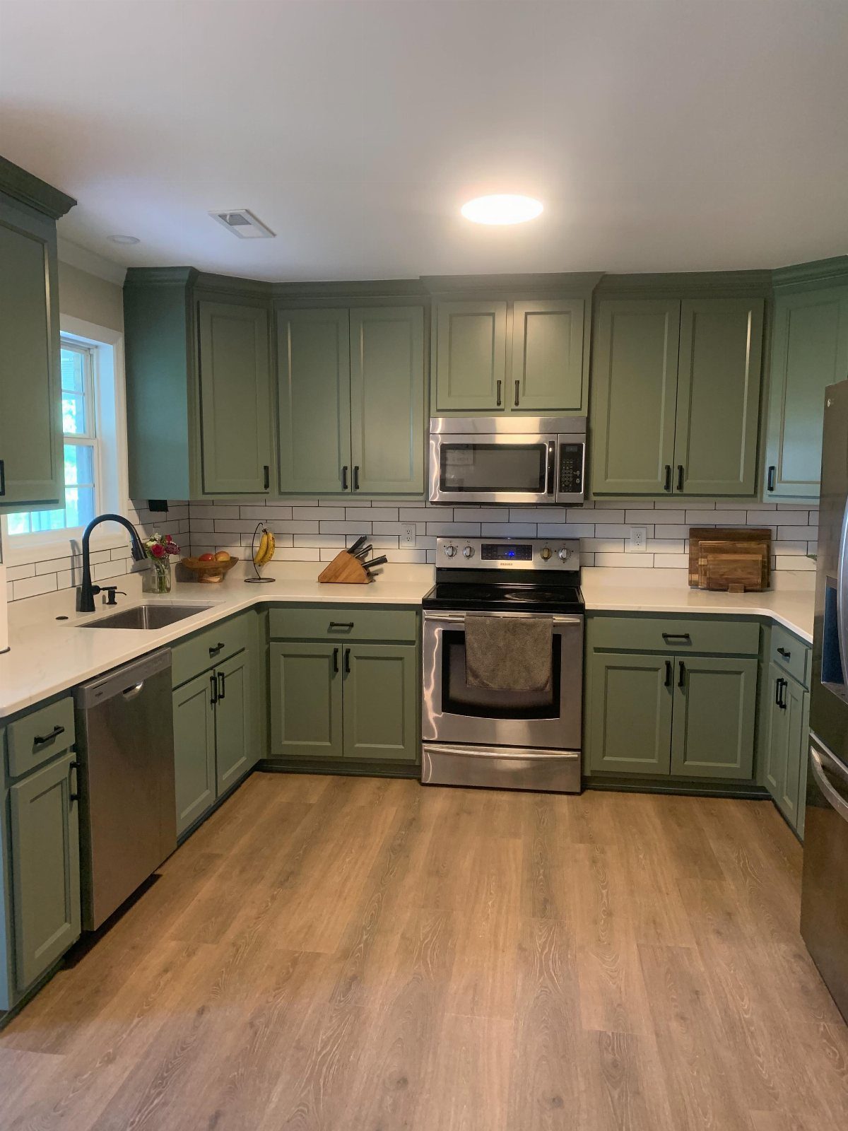 28 Kitchen Cabinets Remodel Ideas and Photos to Try in 2026 12 Sage green kitchen cabinets with white countertops and stainless steel appliances in a bright room.