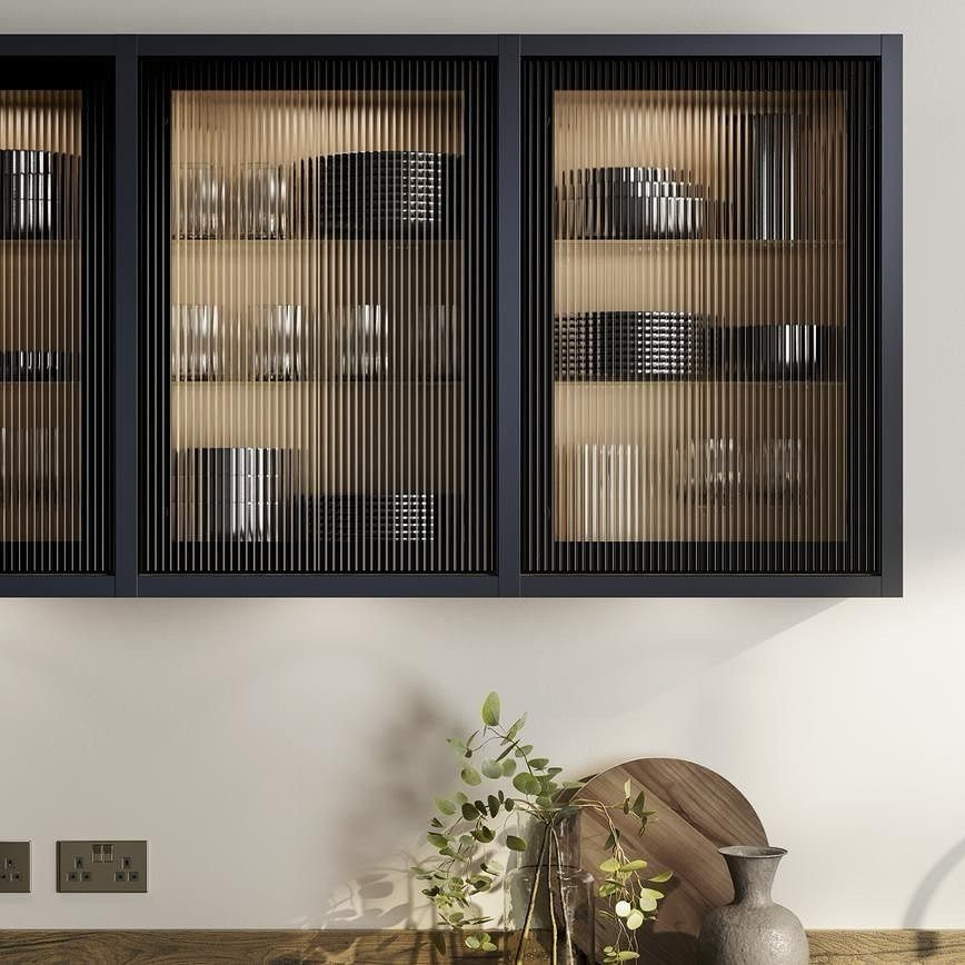 Black wall cabinets with fluted glass doors and interior lighting over a wooden counter.