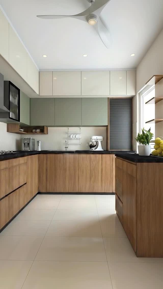 Modern kitchen with sage green cabinets, light wood lower cabinetry, and black countertops.