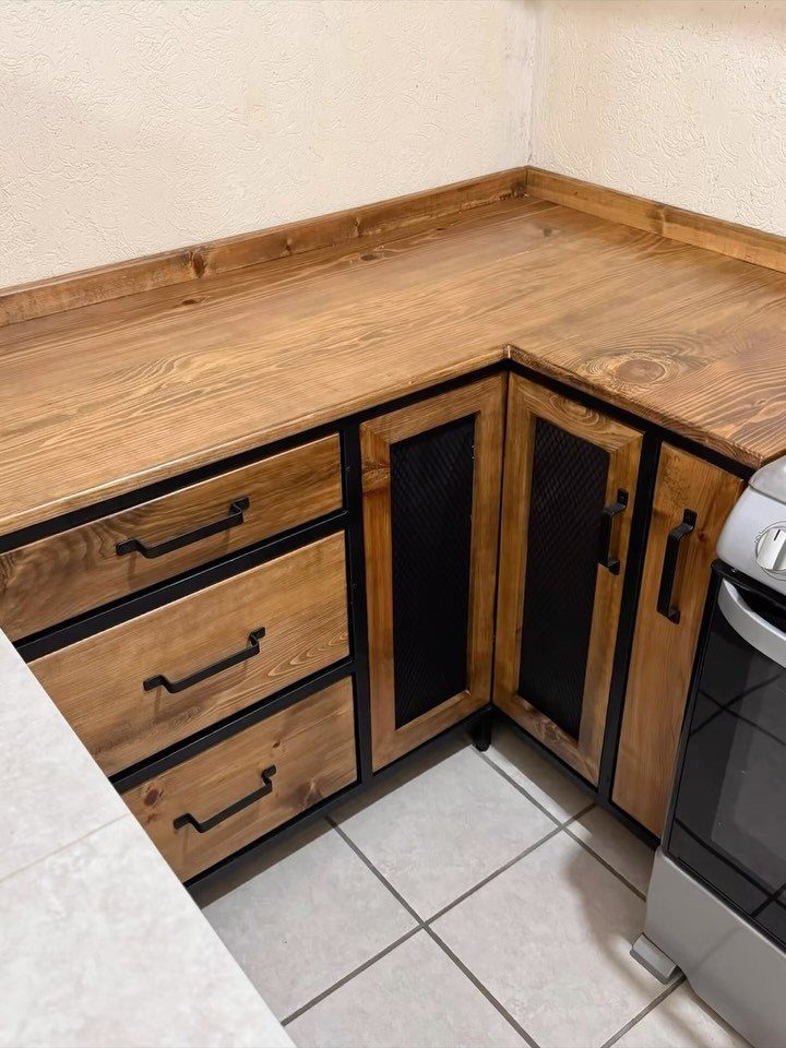 Wooden kitchen cabinets with black metal frames and mesh door inserts in a corner.