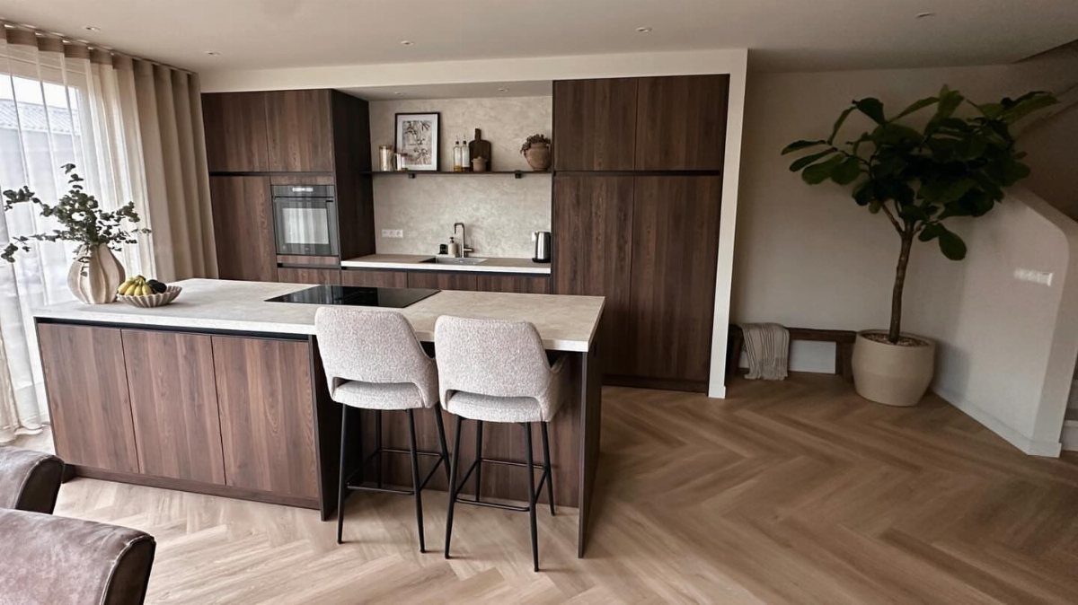 Modern kitchen with dark wood cabinets, white island, and light herringbone wood floors.