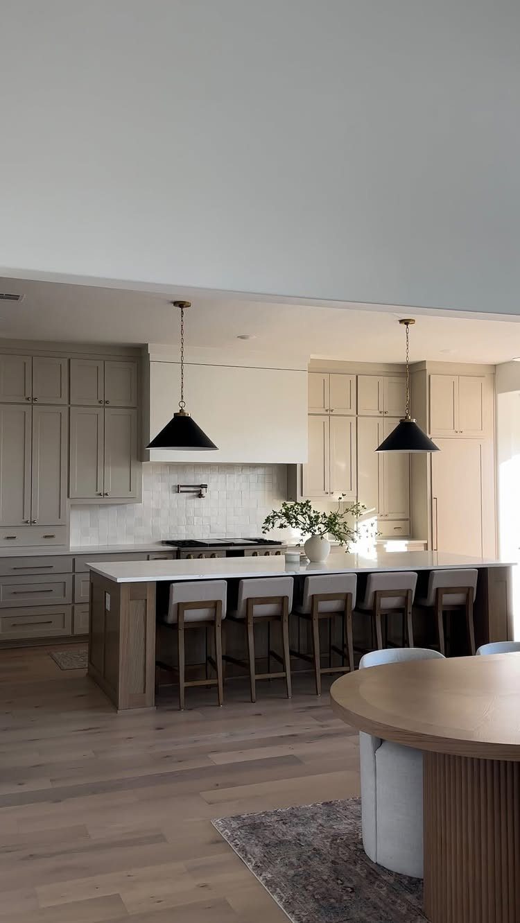 Modern kitchen with grey cabinets, white marble island, and black pendant lighting.