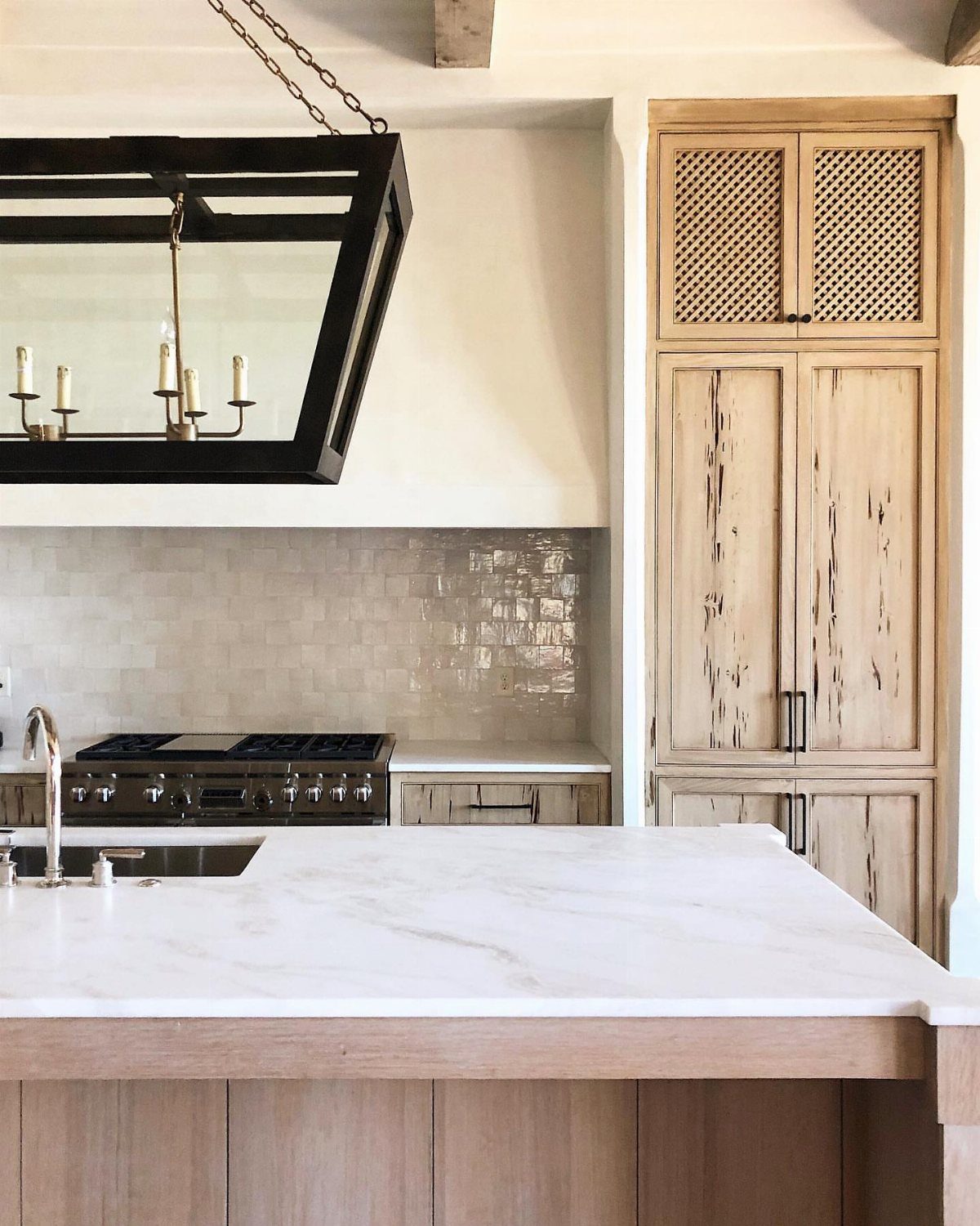Light wood cabinets with pecky cypress grain in a modern kitchen with marble countertops.