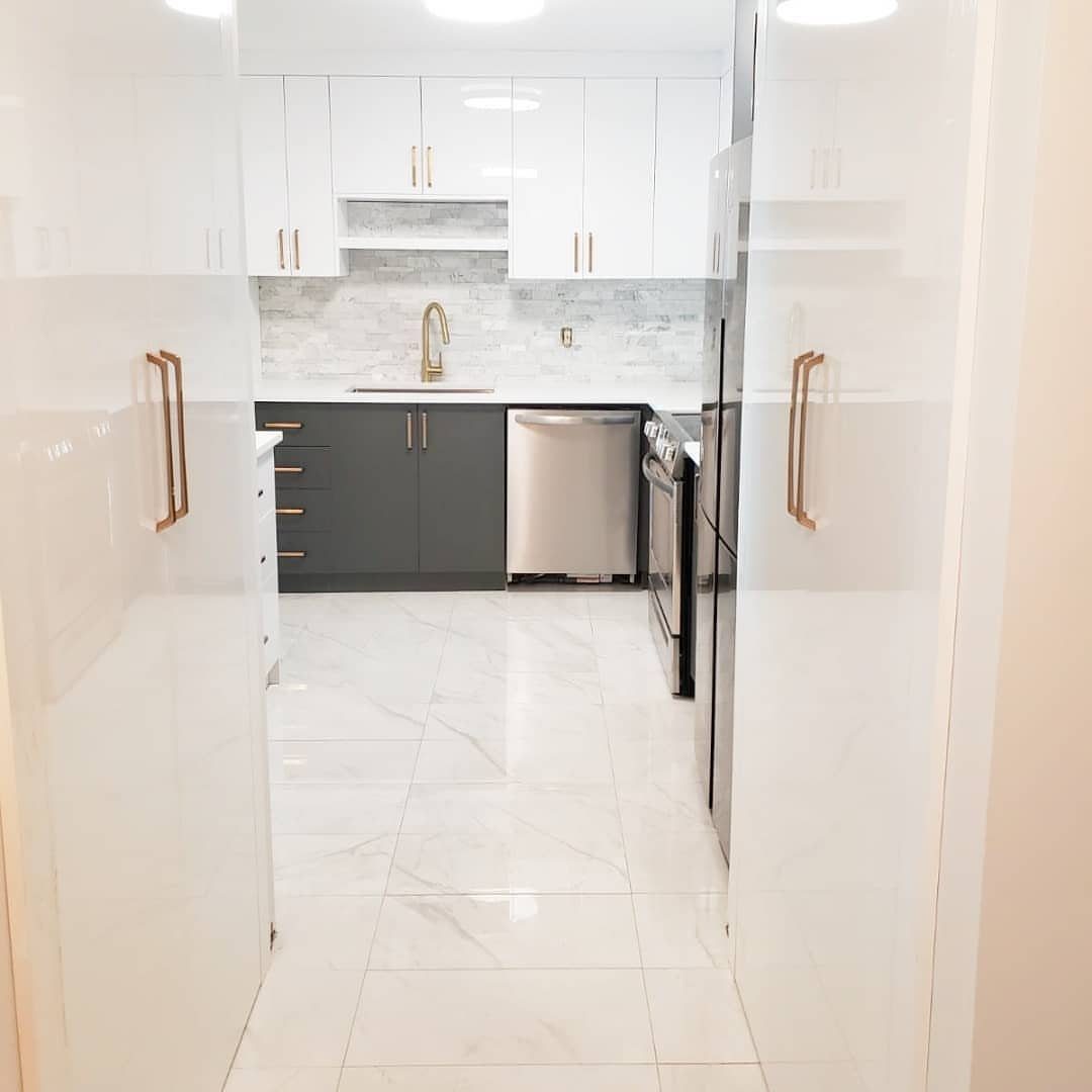 Kitchen with white upper and grey lower cabinets, gold hardware, and marble floors.