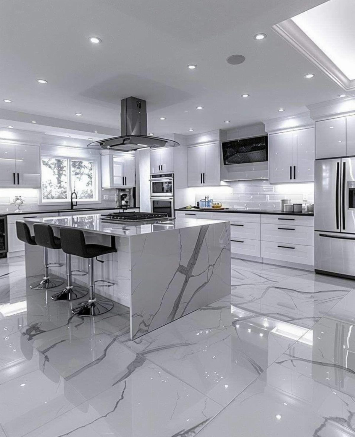 White marble kitchen island and white cabinetry with black countertops and polished floors.