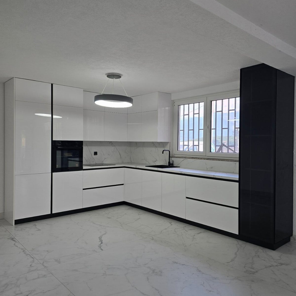 Modern kitchen with glossy white cabinets, black accents, and white marble floors.