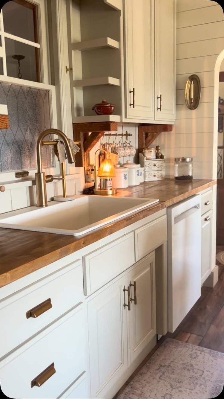 White shaker cabinets and farmhouse sink with wooden countertops in a rustic kitchen.