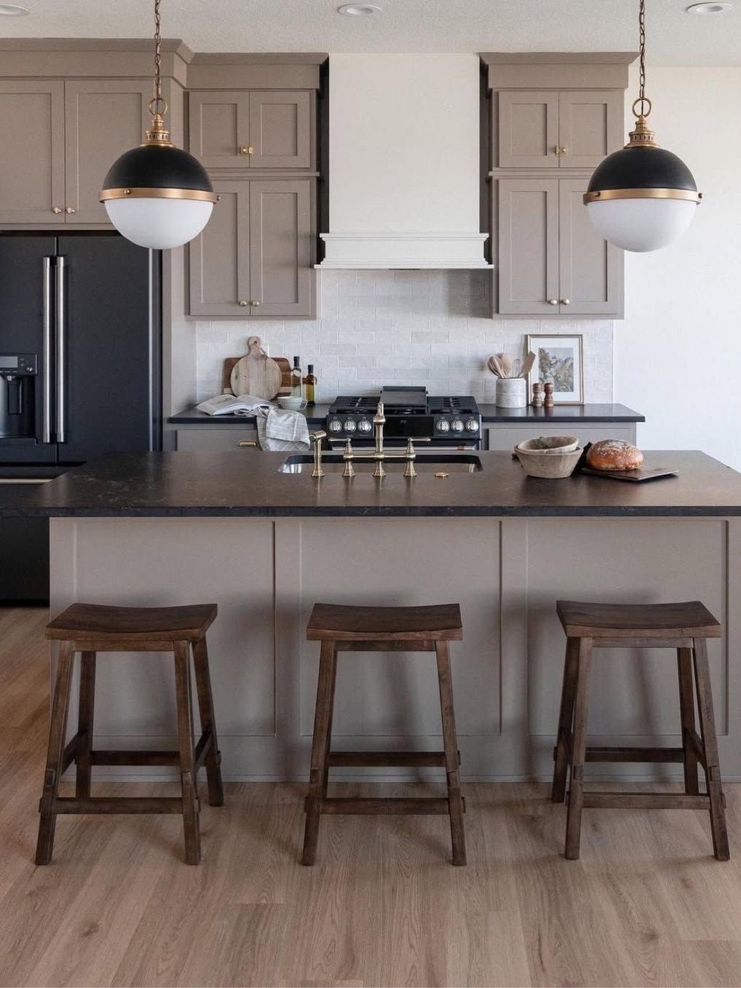 Taupe kitchen cabinets and wooden stools in a rustic room with neutral tones.