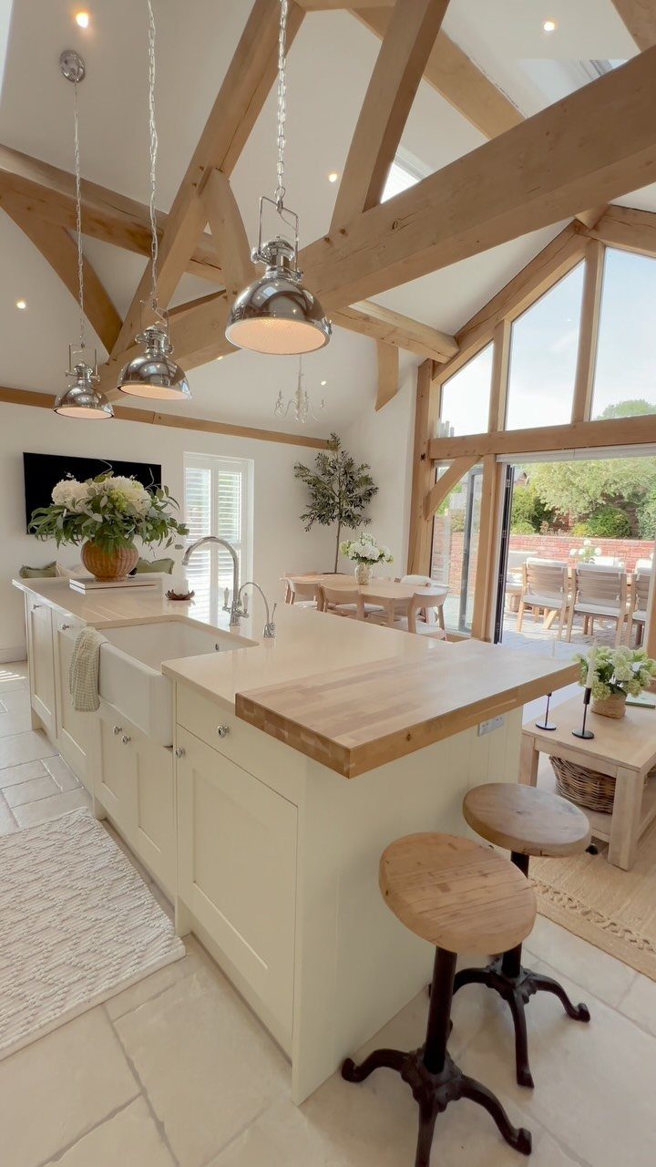 Cream kitchen island with thick wood countertop, farmhouse sink, and wooden stools.